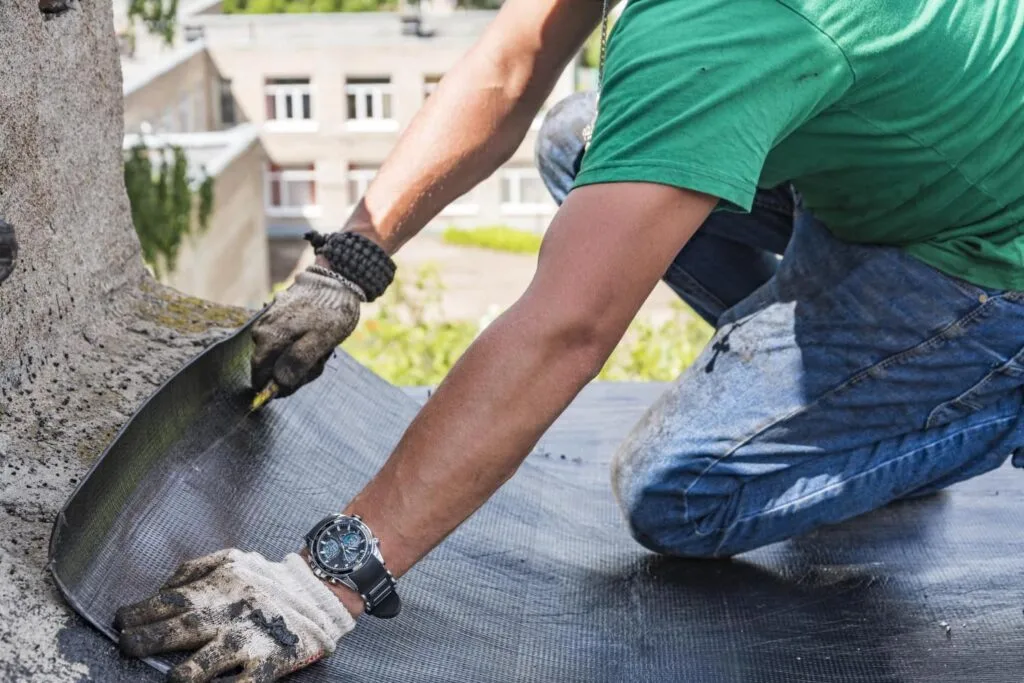 Trabajador aplicando tela asfáltica embreada como impermeabilización
