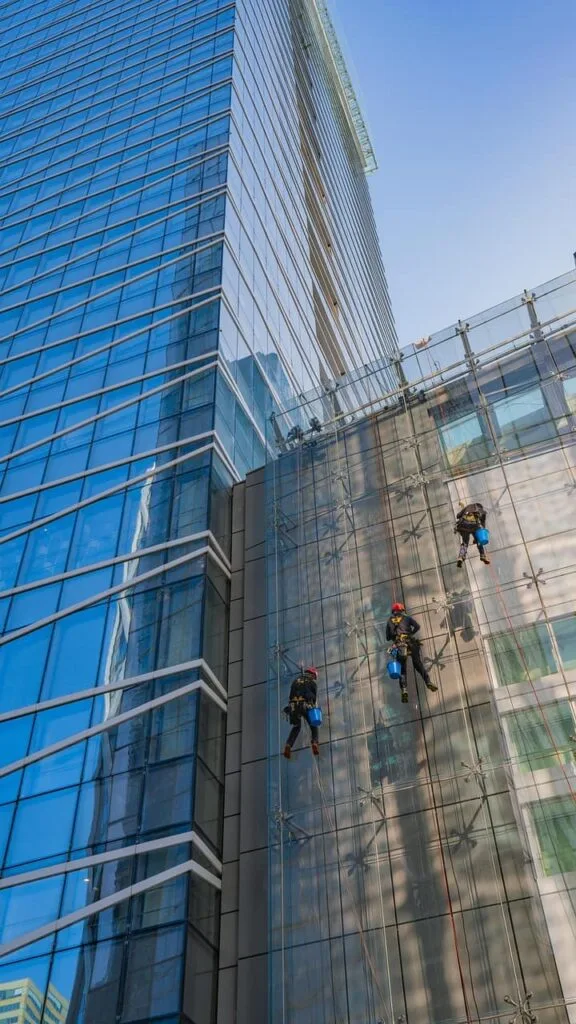 Trabajadores realizando un mantenimiento en fachada tipo muro cortina en altura